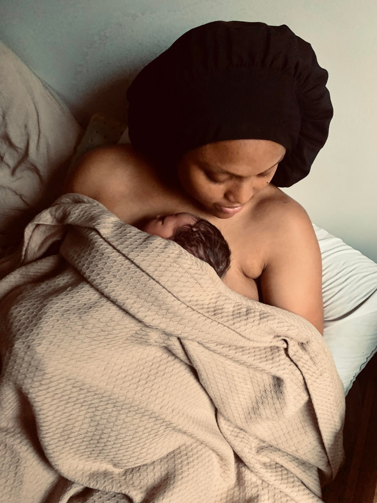 Black mother resting with newborn skin to skin in early postpartum
