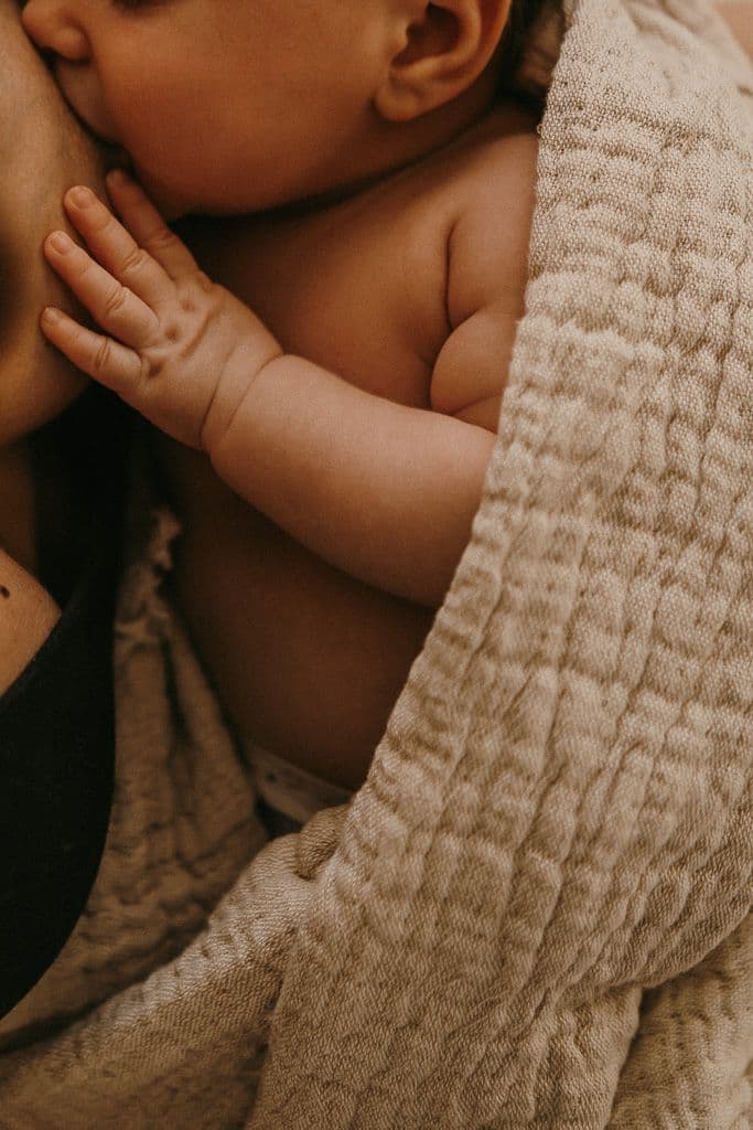 Close up of mother holding newborn baby feet in warm light